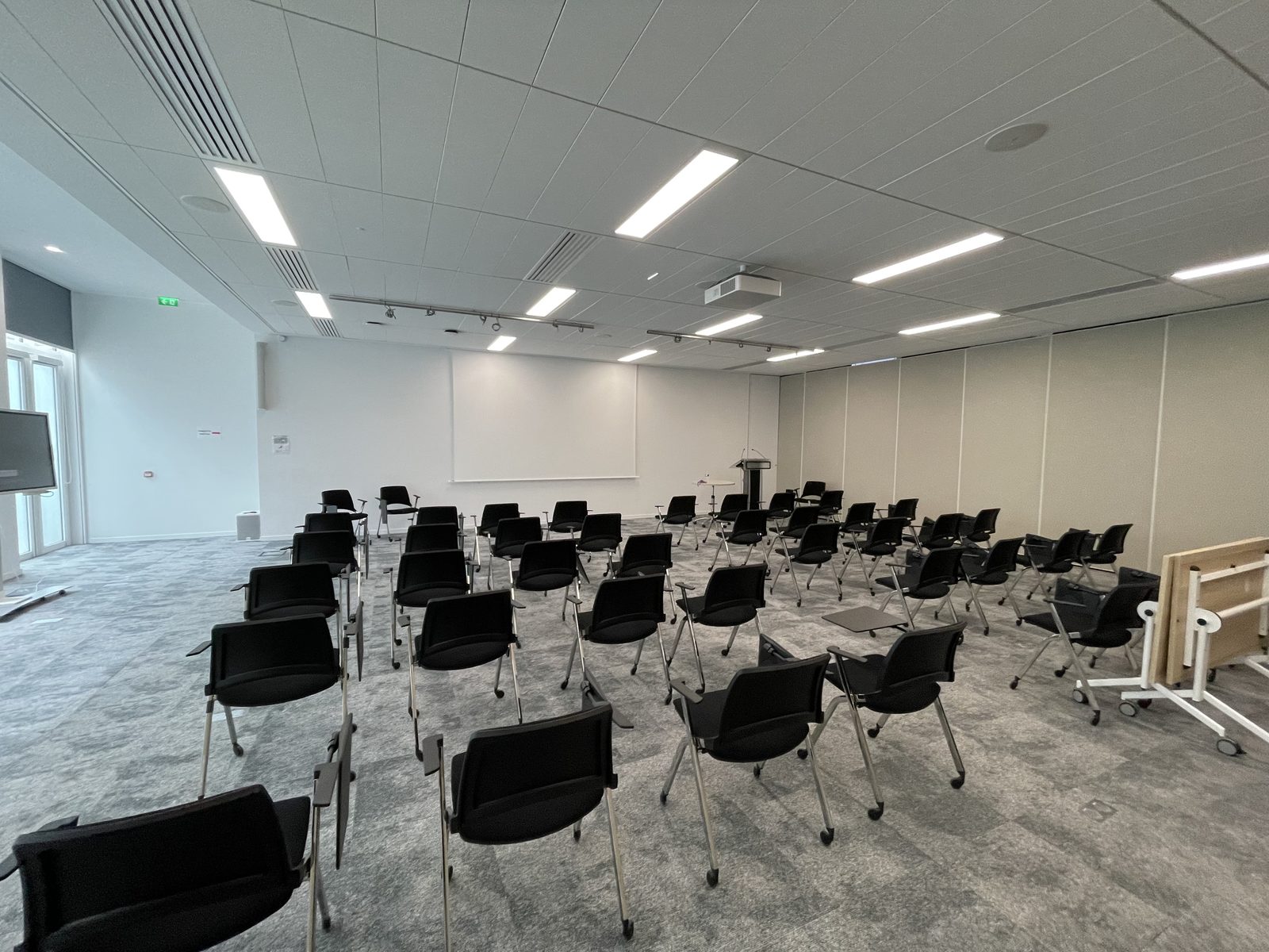 Grande salle vide, chaises tournées vers l'écran, avant un séminaire