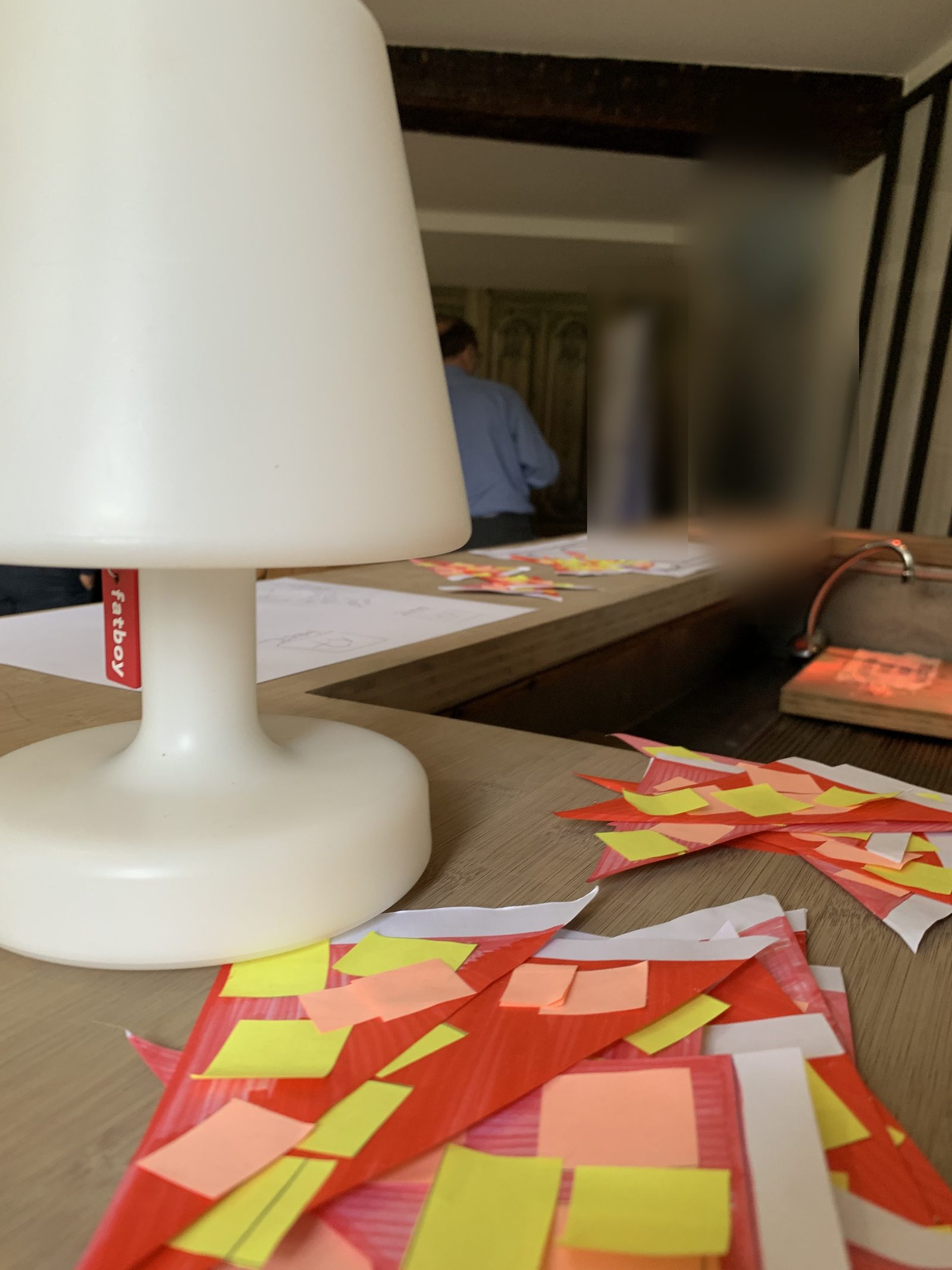 Fin de séminaire : une lampe et des post-it sur la table, la salle se vide